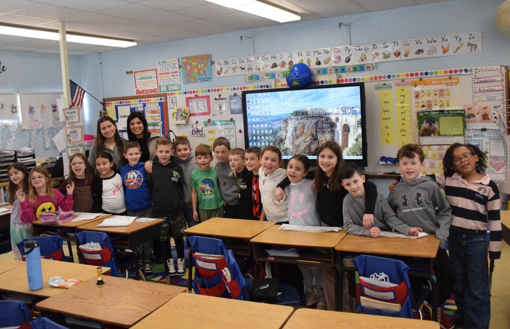 smiling students standing behind desks